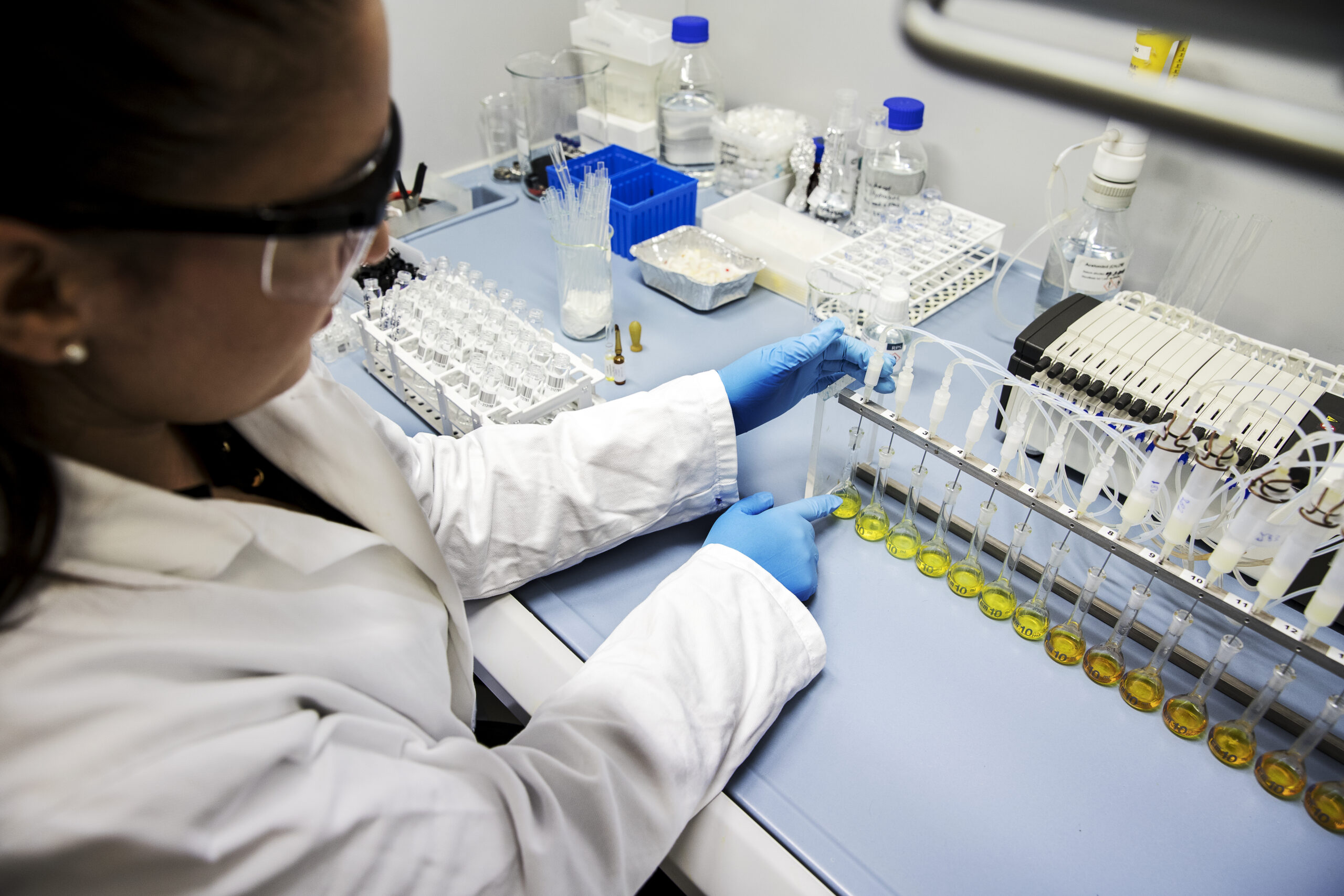 Medewerker in het laboratorium druk bezig met experimenten, kijkt geconcentreerd naar apparatuur en monsters